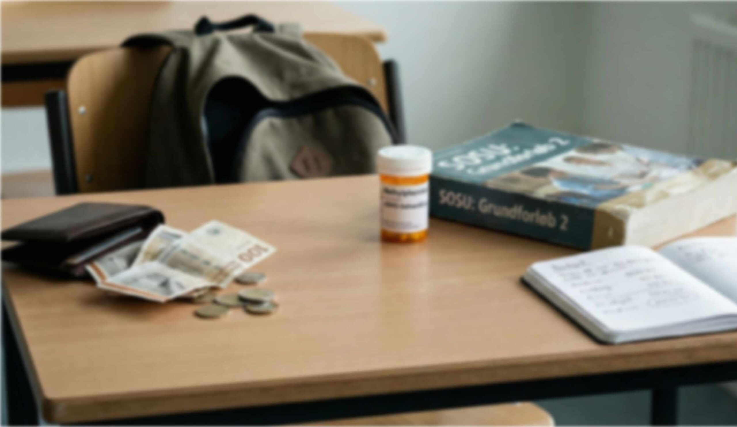 Billede af ADHD medicin på et bord sammen med SOSU bøger og et stramt budget